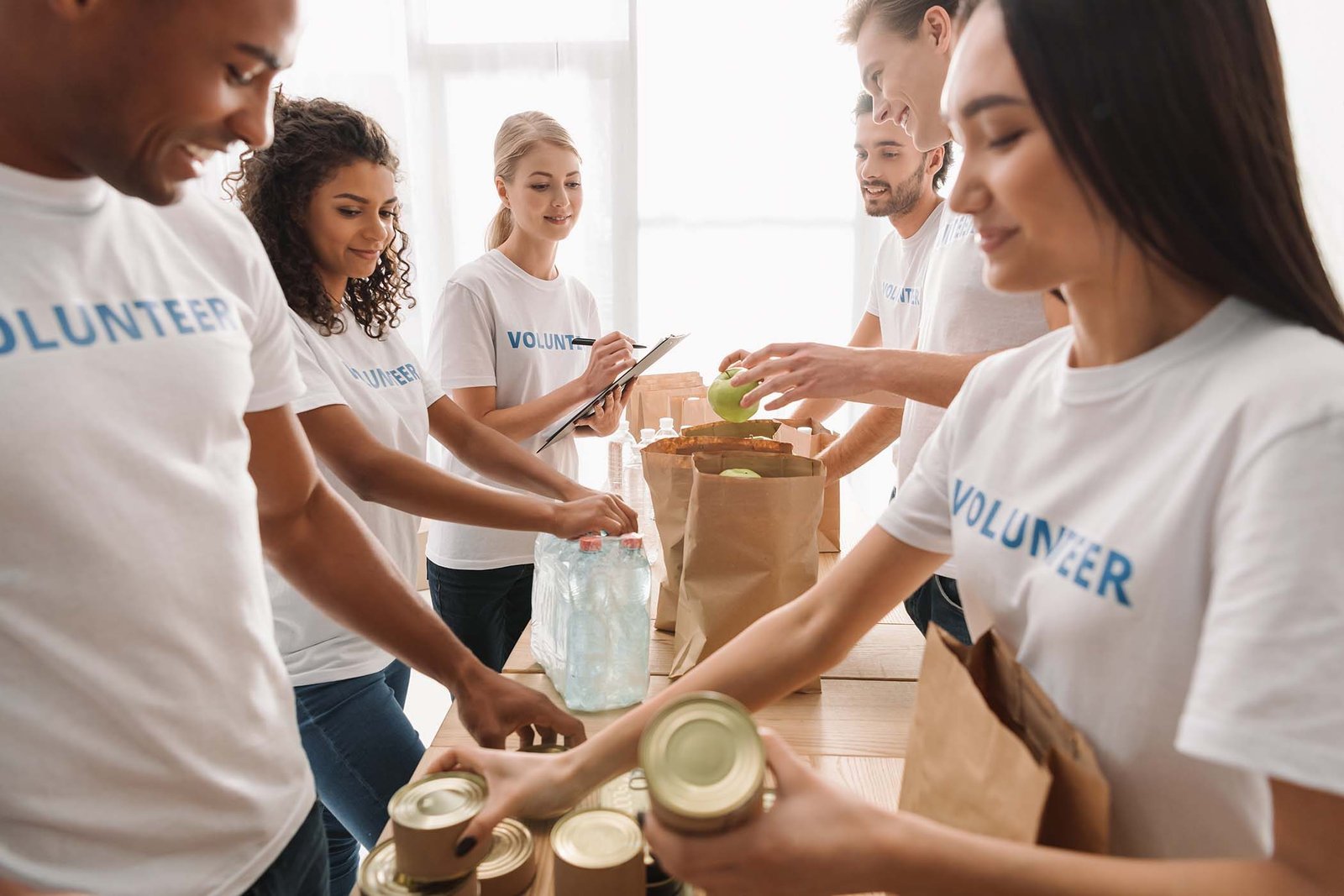 multiethnic-group-of-volunteers-putting-food-and-d-FKDP7L8.jpg